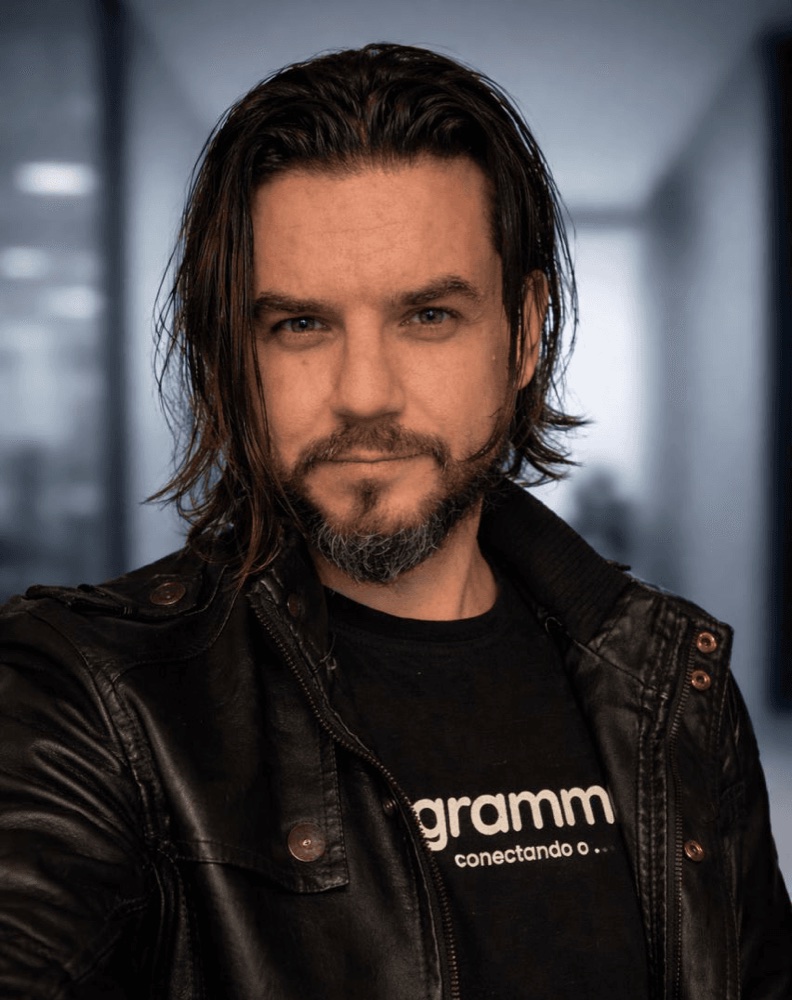 Ric Neves de jaqueta de couro e camiseta da Flowgrammers, no escritório